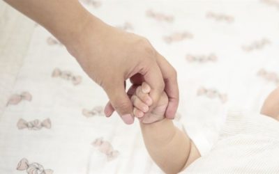 Recién nacido sostiene la mano de su madre